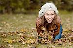 young girl in autumn forest plaing with leaves
