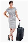 Woman standing next to wheely bag against a white background