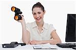 Smiling businesswoman holding binoculars against a white background