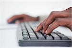 Close up of a masculine hand using a keyboard against a white background