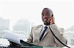 Smiling businessman on the phone while reading a document in his office