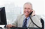 Smiling senior manager on the phone in his office