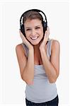 Portrait of a smiling woman listening to music against a white background