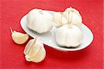 garlic in white bowl over red fabric background