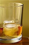 glass of scotch whiskey and ice on gold  background
