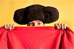 Bullfighter afraid with big montera hidden behind cape humor spanish colors