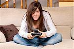 Young female playing video-games concentrating on sofa at home