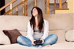 Young female lose playing video-games concentrating on sofa at home