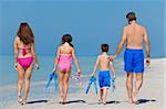 A happy family of mother, father and child, a daughter, walking in swimming costumes on a sunny beach