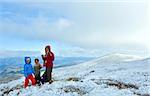 Family (mother with children) drink hot tea on autumn  mountain plateau with first winter snow