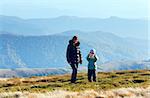 Family (mother with son) walk and make photo on autumn mountain plateau.