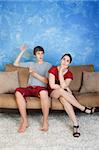 Bored young woman with innapropriately dressed boyfriend on sofa