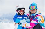 portrait closeup of happy and smiling father and son in ski goggles and a helmet