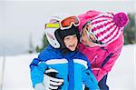 portrait closeup of happy smiling boy in ski goggles and a helmet with his mother