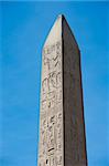 Large ancient obelisk with egyptian hieroglyphics at Karnak temple in Luxor against a blue sky background