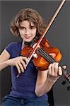 Photo of a young girl practicing the violin over a dark background.