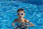 Boy with spectacles in the swimming pool with clear water