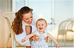 Young mother in bathrobe playing with baby on terrace