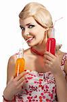 Young pretty girl with color make up hairstyle and color dress drinking from colored bottle some drink, she is turned of three quaters, looks in to the lens and drinks by orange bottle