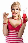 Young pretty girl with color make up hairstyle and color dress drinking from colored bottle some drink, she looks in to the lens, bites the lollipop and takes the red bottle with right hand.