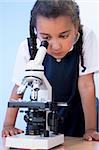 A beautiful young mixed race African American girl child using a microscope in a school laboratory