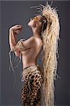 alluring and sexy woman with raffia hair and a ethnic costume in a shot over dark with creative make up