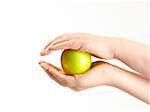 Apple sandwiched between childs hands - on white background