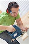 Man cutting wood with electric saw at the workbench