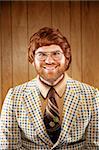 A Portrait of a handsome Game Show host in Retro Clothing. the game show host is wearing a vintage sports coat and a brown retro tie. He is against a dark wood paneled backdrop.