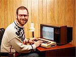 A Handsome and Nerdy Adult using a Vintage Commodore Vic-20 64 computer on a Retro TV.