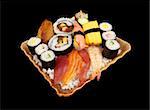 Various pieces of sushi stacked on a plate on a pile of white rice isolated on black.