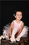 Cute little brunette girl trying on ballet pointe shoes