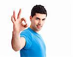 Portrait of a smiling handsome young man gesturing ok sign over a  white background