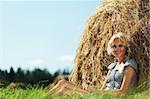 portrait of a girl next to a stack of hay under the blue sky