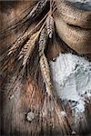 Wheat ears and flour sack on grunge wooden board