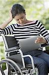 Black Woman in a wheelchair reading a Digital Tablet