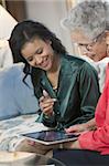Mature Black woman sharing a digital tablet at a home meeting with her agent
