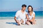 Happy family of three sitting and having fun on tropical beach