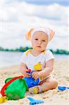 cute baby girl playing on the beach with sand. Vertical view