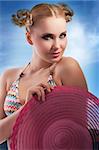 fashion shot of blond sensual girl in pink bikini and pareo taking pose with hat and hair style