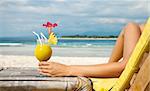 Woman holding a fruit cocktail on a tropical beach