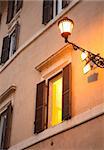 Vintage lantern on the wall near glowing window