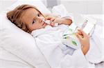 Little girl with bad cold in bed - using nasal spray and paper napkins