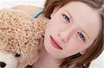 Beautiful sad girl holding teddy bear and crying - closeup