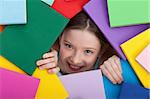 Happy young girl emerging from beneath books - education and learning concept