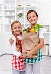Happy healthy kids in the kitchen with the grocery bag full of vegetables
