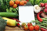 Ruled shopping list with fresh vegetables on a wooden background