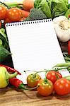 Ruled shopping list with vegetables on a wooden background