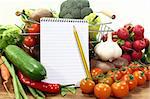 Shopping list with basket, pencil and fresh vegetables on a wooden background