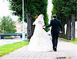 bride and groom is running with joined hands on city park road